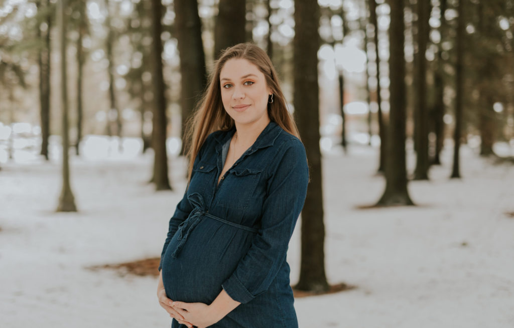 A new mother poses with her baby bump during a winter maternity session in Stratford, Ontario