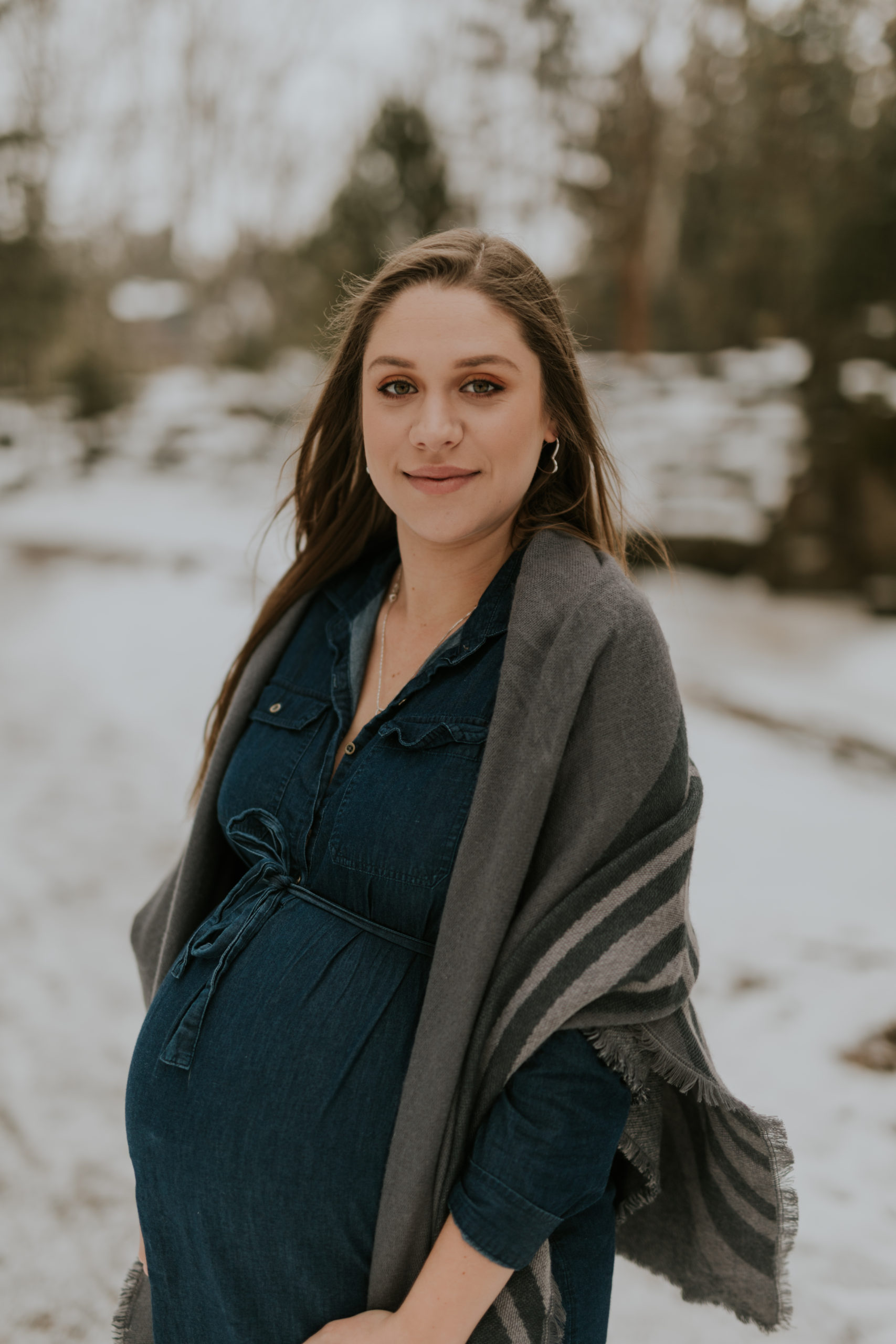 A new mom poses with her baby bump during a winter maternity session with Cara Gilhula Photography in Stratford, Ontario at Upper Queens Park