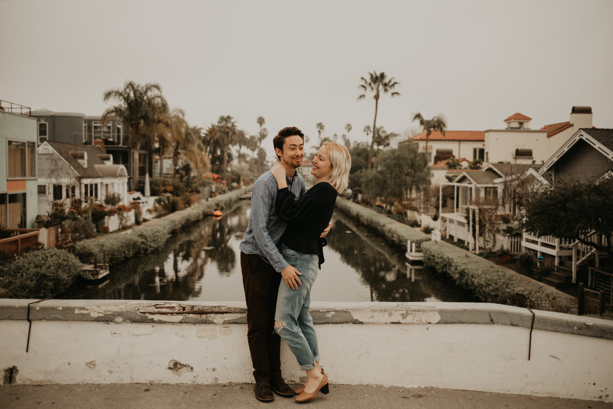 Couple laughs during couple session with Cara Gilhula Photography at Venice Canals, California