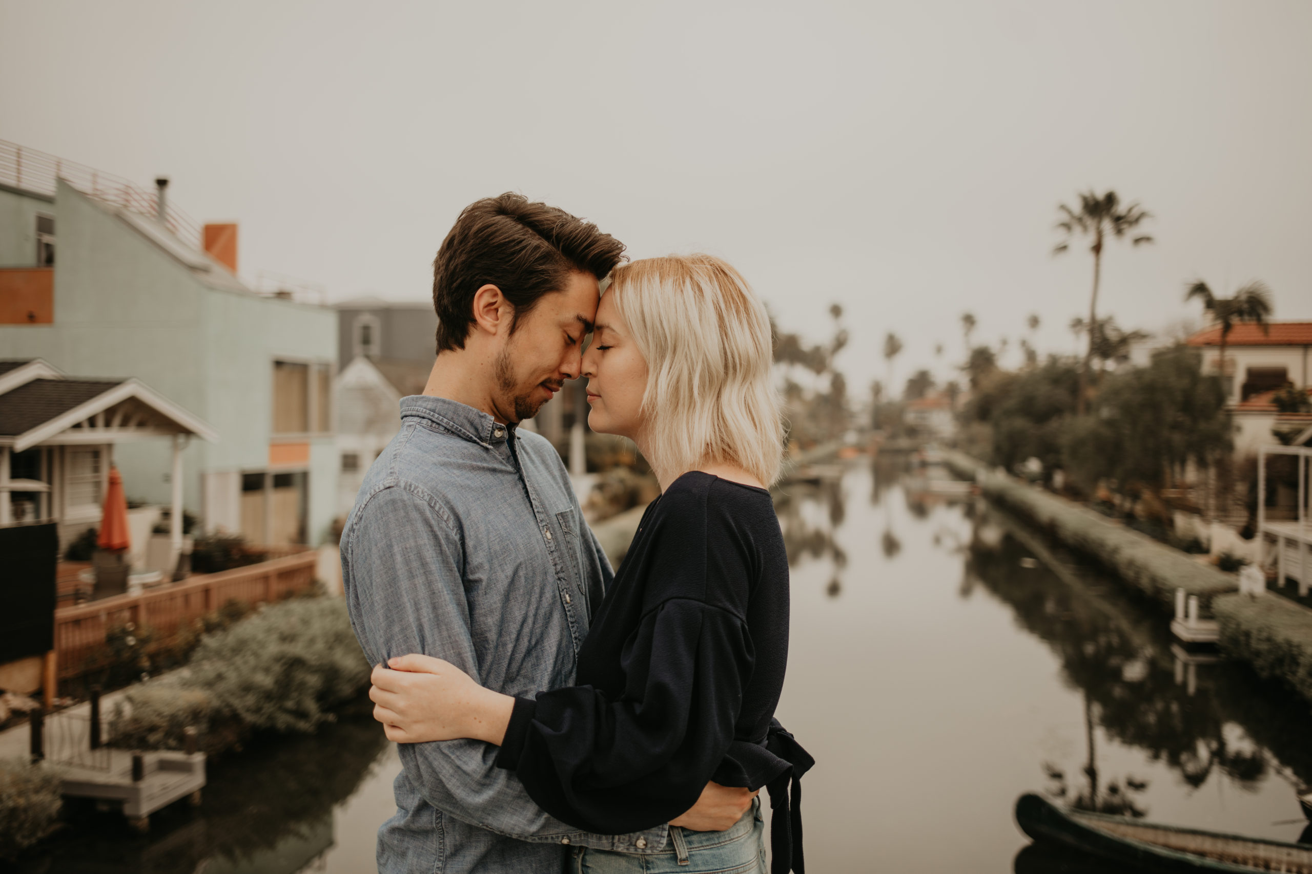 Couple goes nose to nose during couple session with Cara Gilhula Photography at Venice Canals, California
