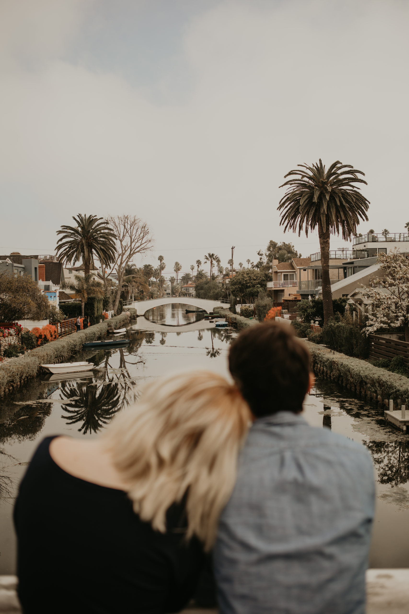 Couple cuddles during couple session on bridge with Cara Gilhula Photography at Venice Canals, California