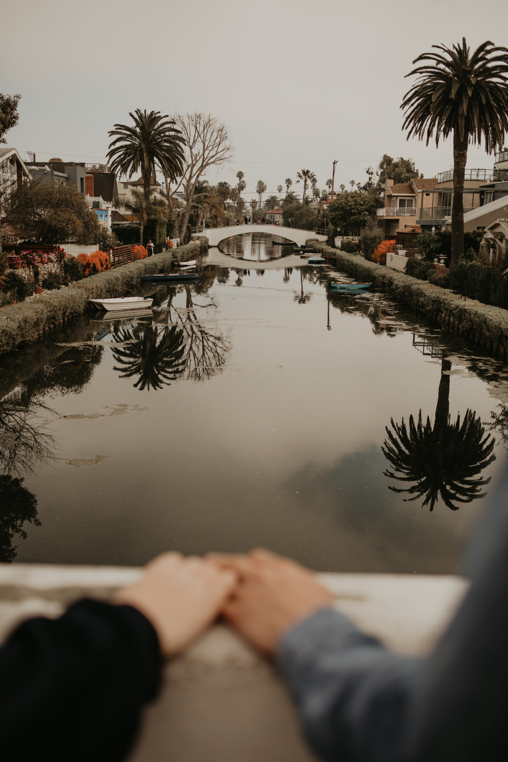 Holding hands during couple session on bridge with Cara Gilhula Photography at Venice Canals, California