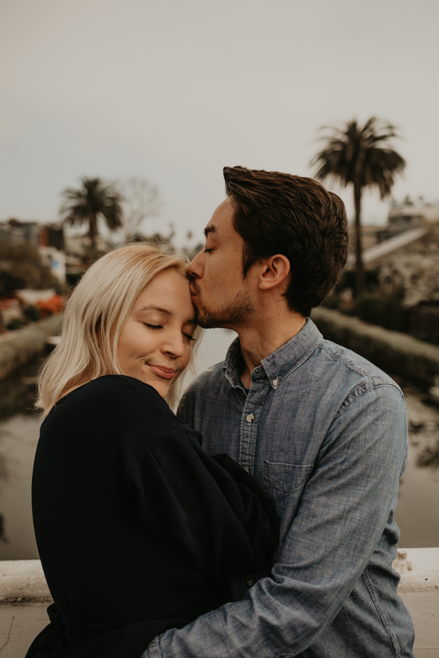 Boyfriend kisses girlfriend on forehead at Venice Canals, California with Cara Gilhula Photography