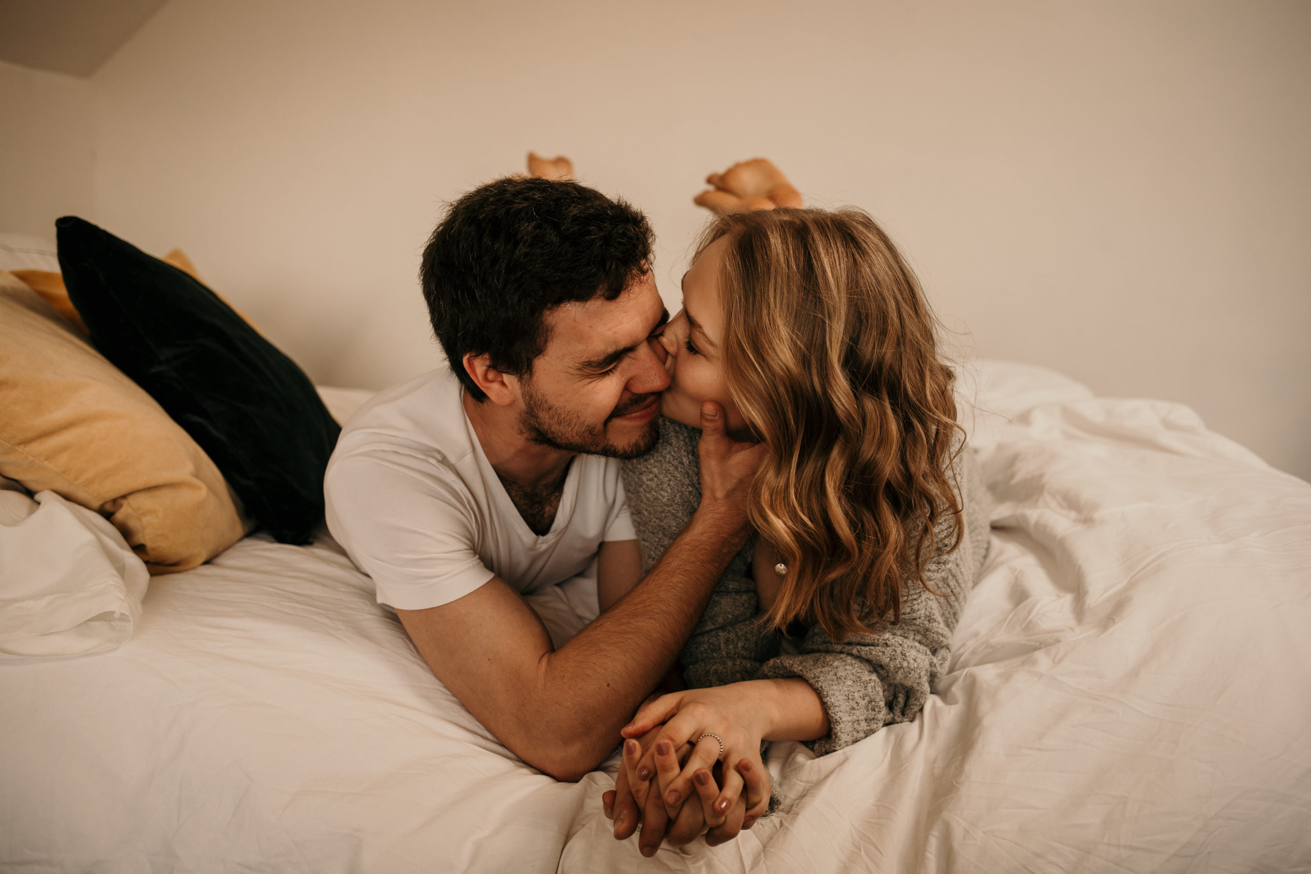 Couple shares a cheek kiss during an in-home couple session with Cara Gilhula Photography
